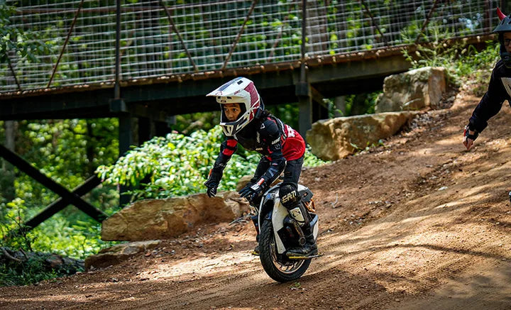 A helmeted electric unicycle racer descends a dirt course at Amped Electric Games.