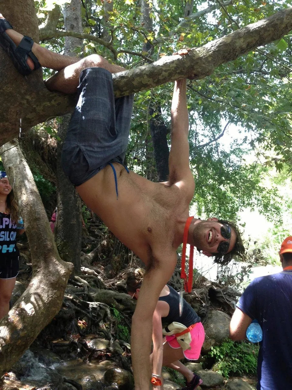 Ari Zimmerman hanging playfully from a tree during a river hike.