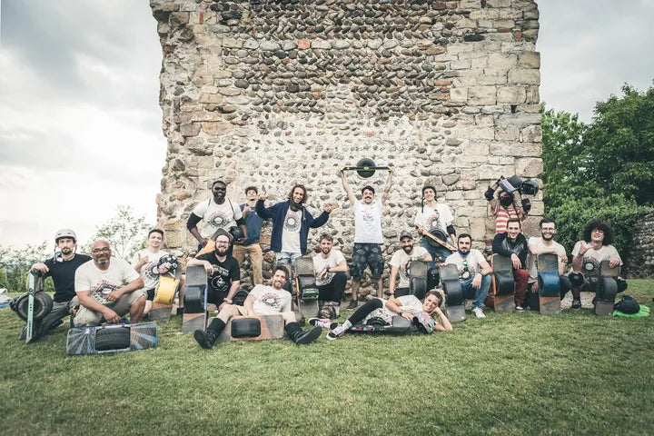 Float Italia riders pose with their Onewheels in front of a stone wall.