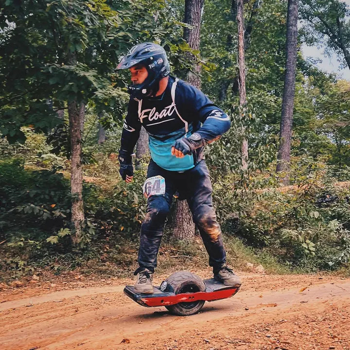 Jamie Trusheim riding a Onewheel on a wooded dirt trail.