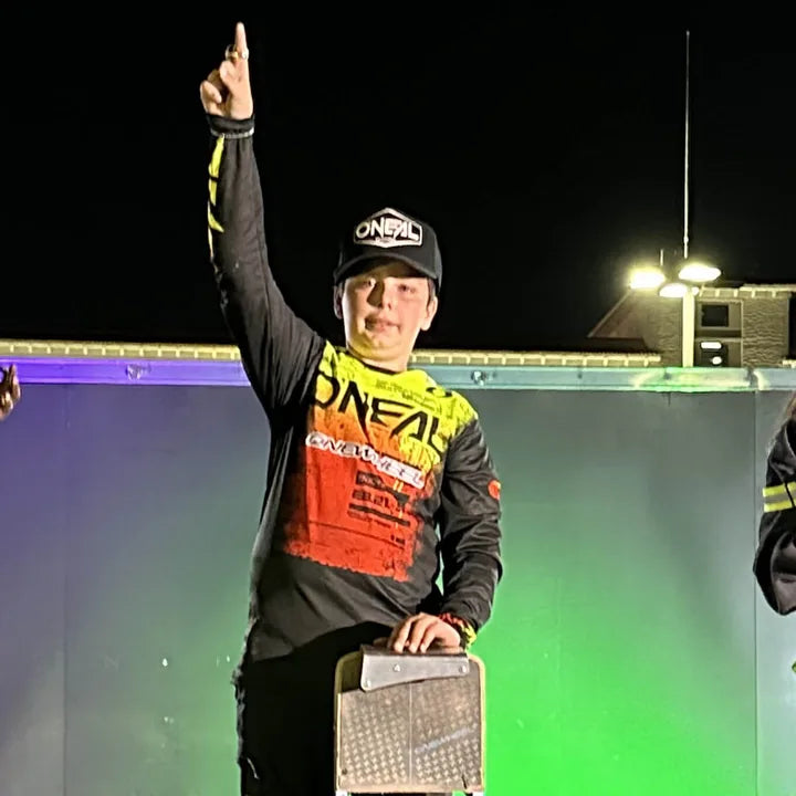 Mason O'Neal raising one finger with his Onewheel at a race podium.
