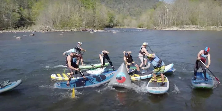 Stand-up paddleboarders cluster around a course marker on the river at NoliFest 2022.