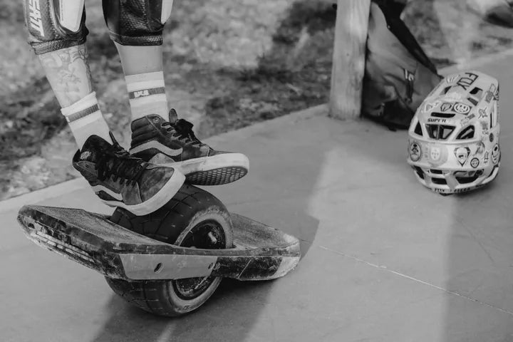 Black-and-white close-up of a rider's feet carving on a Onewheel