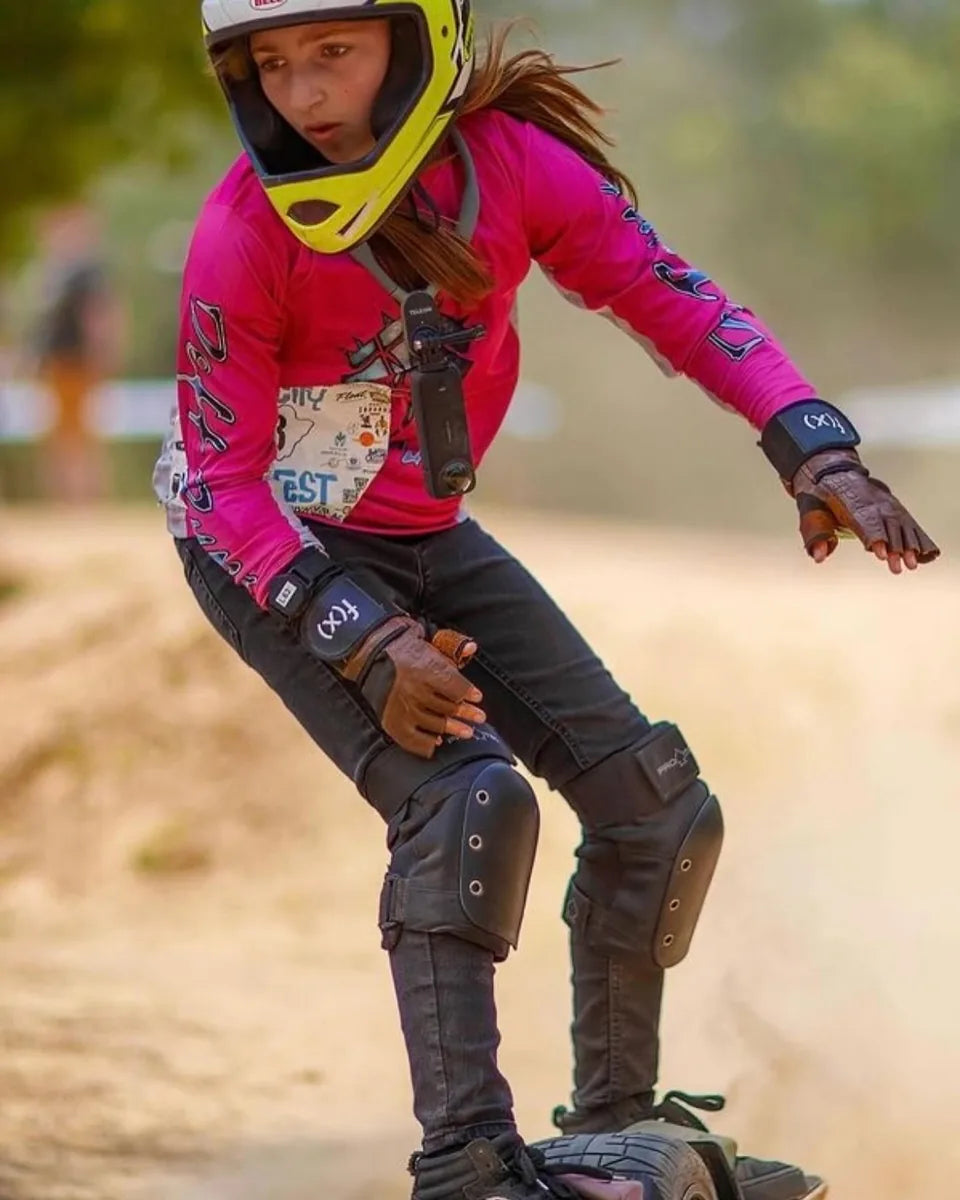 Zoey Miller leaning into a race turn in a pink jersey on her Onewheel.