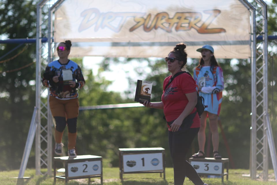 Three riders stand with prizes on the Dirt Surferz awards podium.