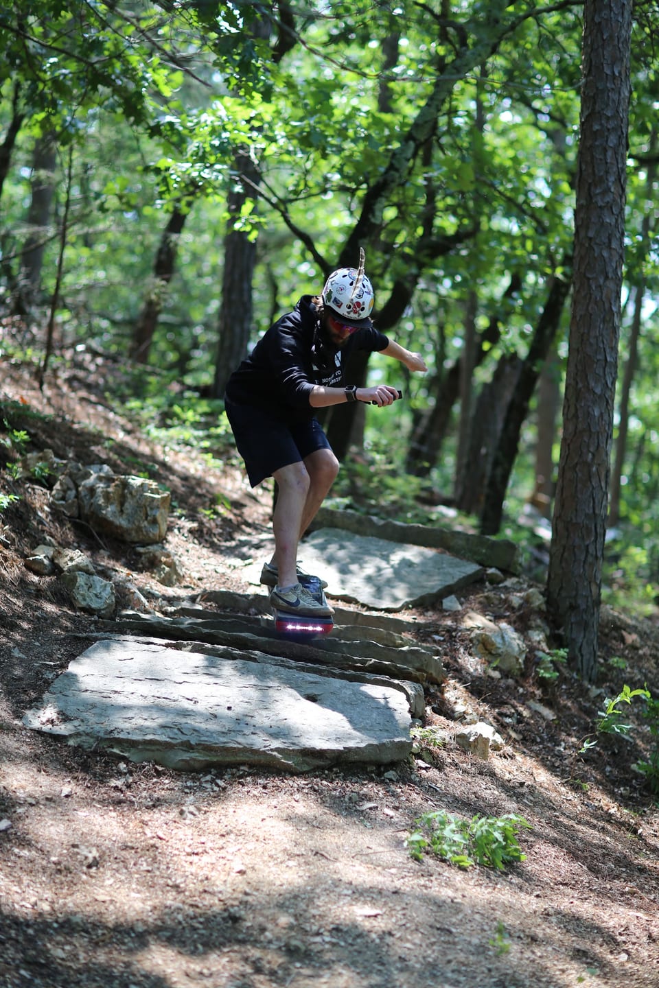 A helmeted rider works through a steep, rocky forest line at Dirt Surferz.