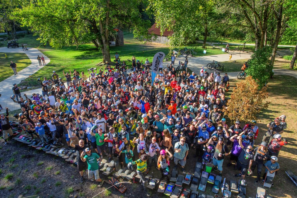A large crowd of riders gathers on a green lawn for the Floatlife Fest 4 group photo.