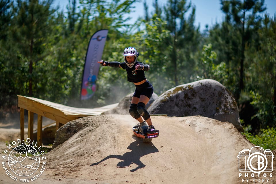 A helmeted rider in blue and purple carves over a dirt roller at Oak City Shredfest.