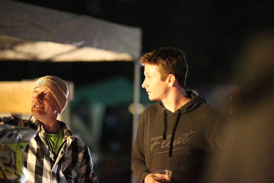 Two attendees talk beside a lit nighttime stage at Oak City Shredfest.