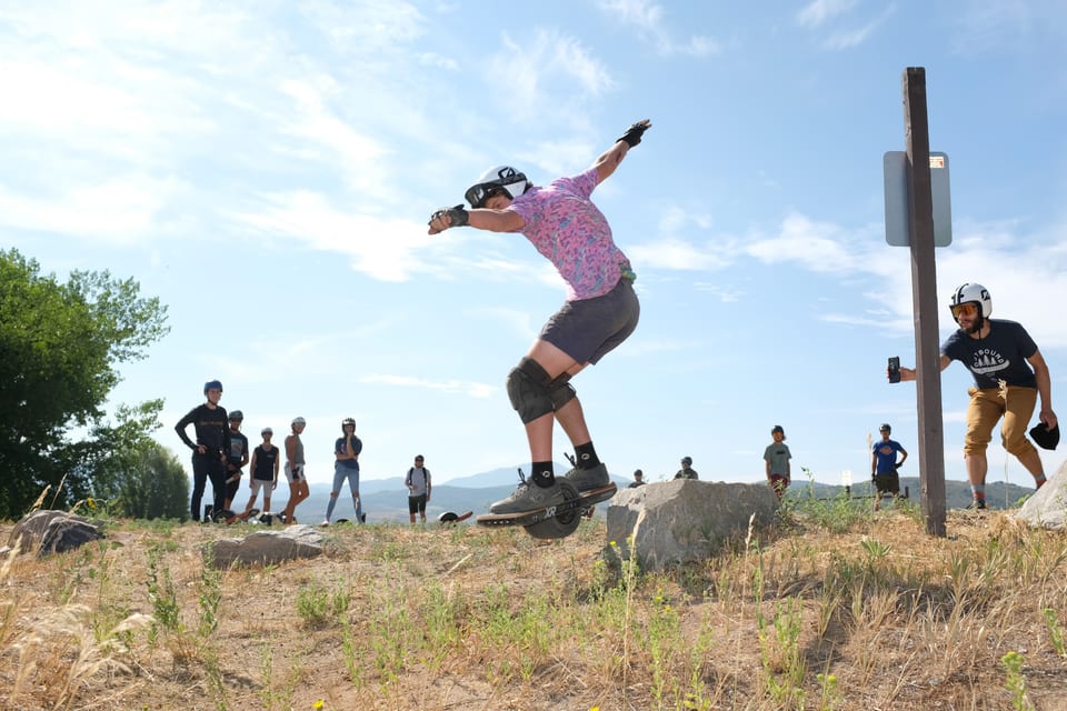 A helmeted rider drops a rock line while spectators watch at Race for the Rail.