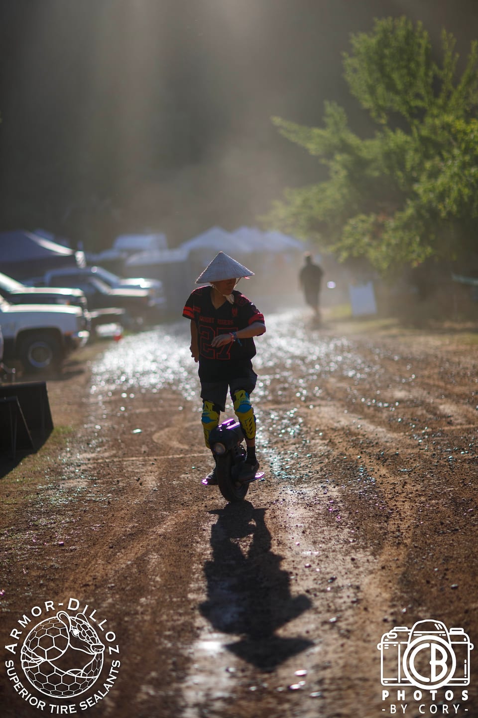 A rider in a conical rain hat rolls along a wet, wooded course at Seek N' Shred.