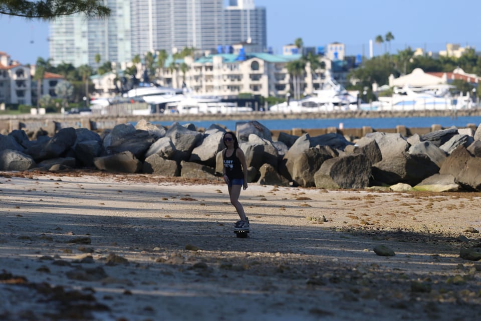 A lone rider cruises a waterfront path with the city beyond.