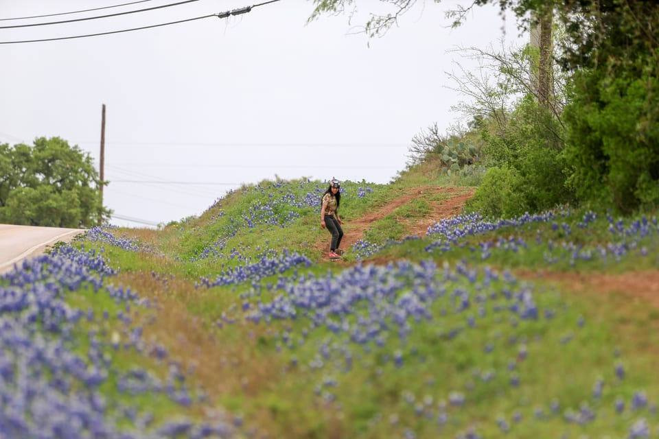A rider descends a dirt line through bluebonnets at Underground x Lemonade Float Fest.