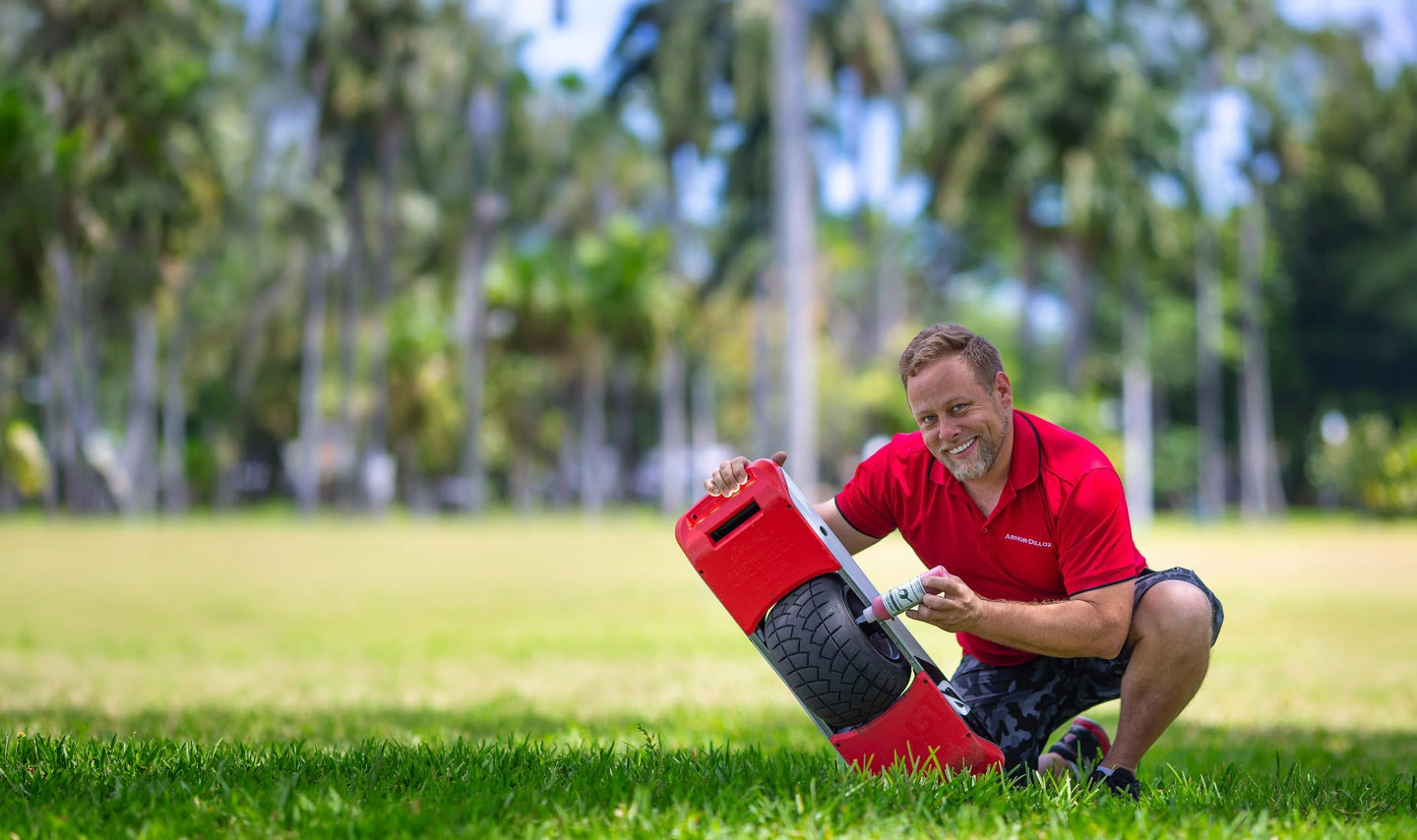 Cory Boehne holds a bottle of Armor-Dilloz beside the tire of a red Onewheel.